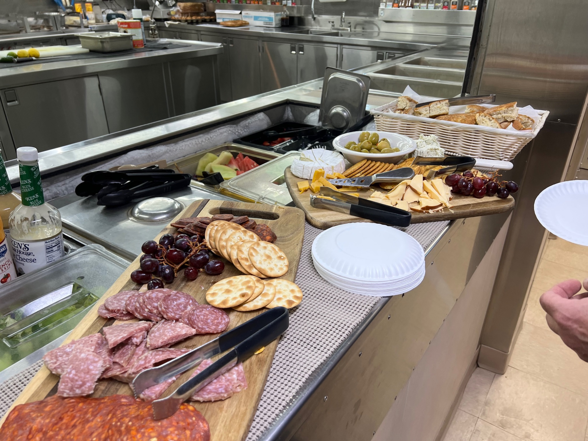 Two charcuterie boards filled with grapes, cheeses, crackers, meats, and olives are on the counter outside of the kitchen area.