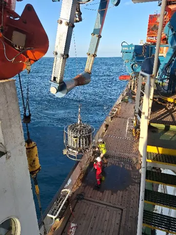View from above looking down at two people helping recover CTD rosette from the side of the ship.