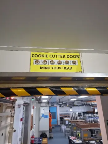 A sign from inside the ship that says "Cookie Cutter Door. Mind your head!"