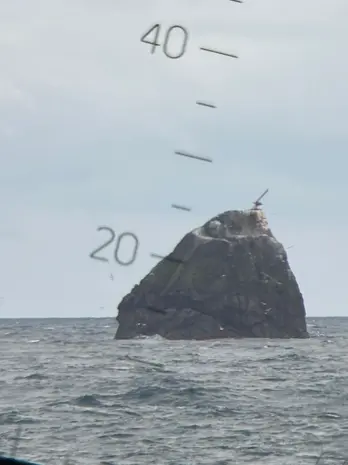 A large rock sticks out of the ocean.